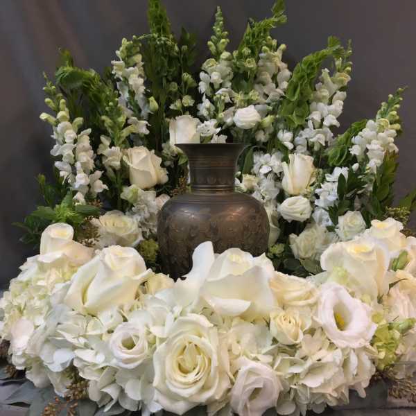 White floral funeral arrangement with a dark urn in the center