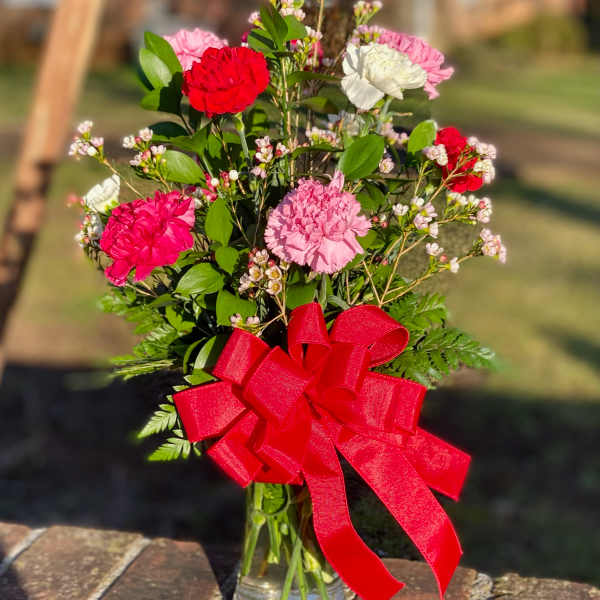 Carnation bouquet in a glass vase with a red ribbon