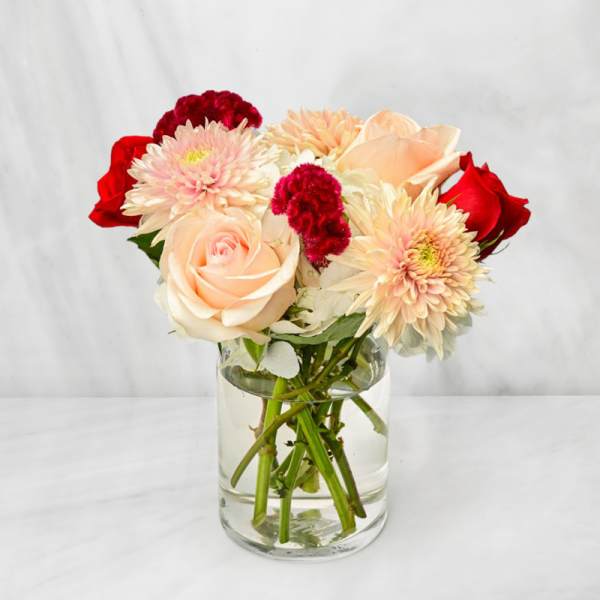 Bouquet of pale pink and red flowers in a clear glass vase