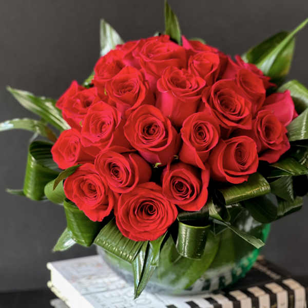 Bouquet of red roses with glossy green leaves in a vase