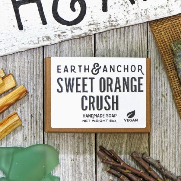 Boxed handmade soap labeled Sweet Orange Crush on a rustic wood surface