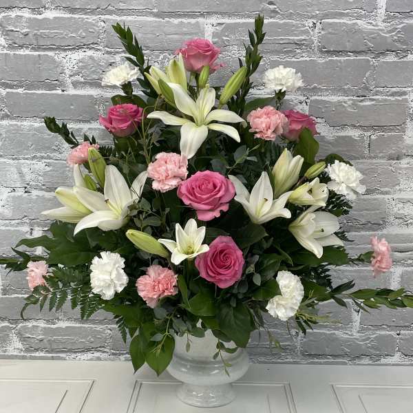 Pink roses and white lilies arranged in a white vase