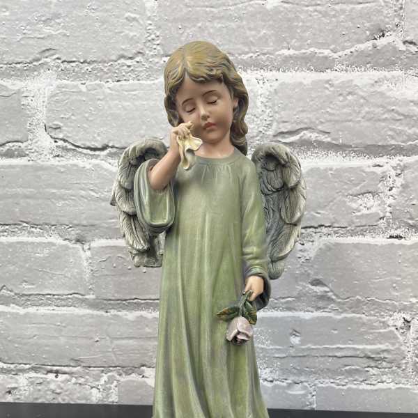 Angel figurine holding a small flower and a cloth