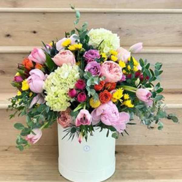Mixed bouquet in a white hatbox with pink, yellow, and green blooms