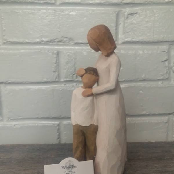 Wooden figurine of a mother holding a child, with a small product card in front