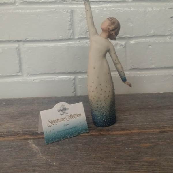 Decorative figurine of a woman in a long dress with one arm raised