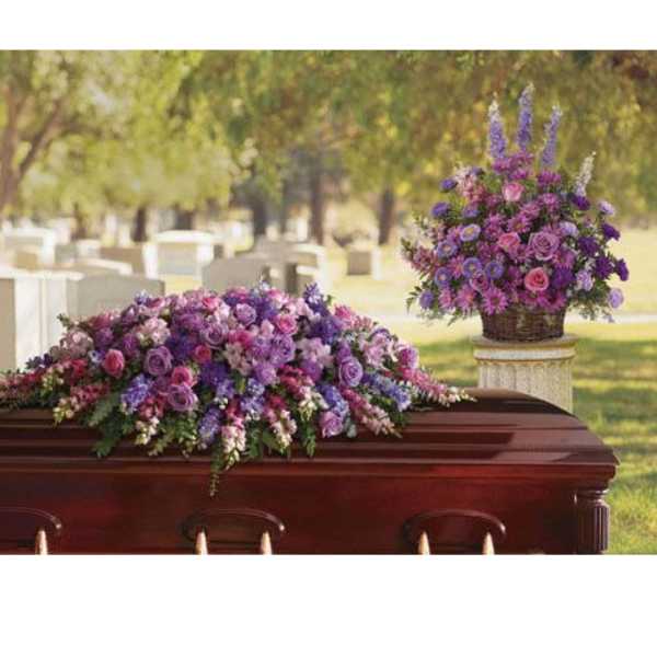 Purple and pink floral casket spray with a matching basket arrangement
