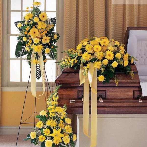 Yellow floral funeral casket spray with matching standing and floor arrangements