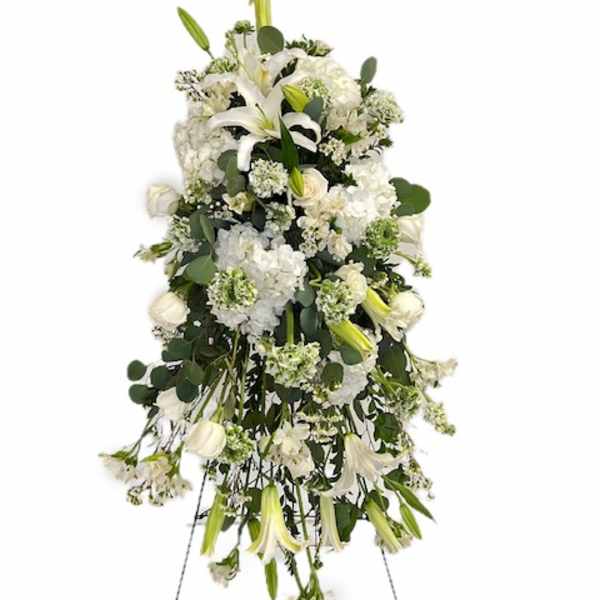 White funeral spray with lilies and roses on a standing easel