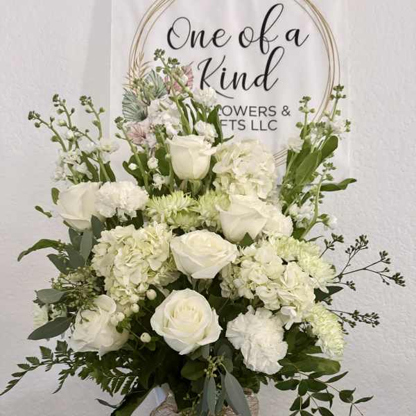 White roses and hydrangeas arranged in a white vase with greenery