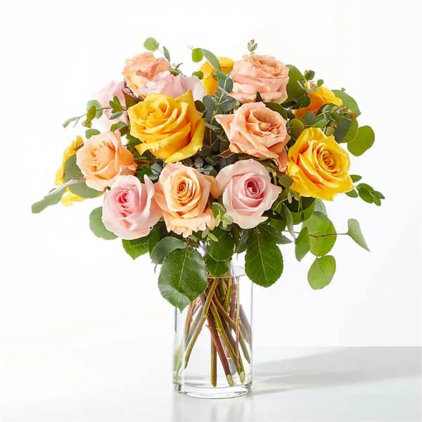 Bouquet of pink and yellow roses in a clear glass vase