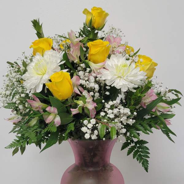 Yellow roses and white daisies in a pink vase
