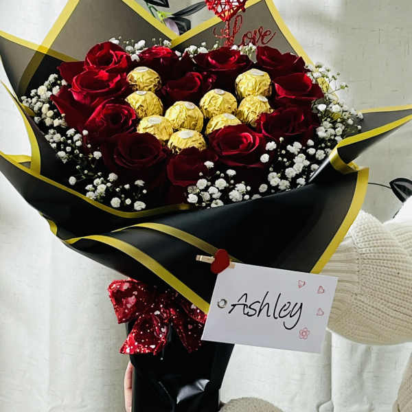 Bouquet of red roses with gold-wrapped chocolates and a heart topper