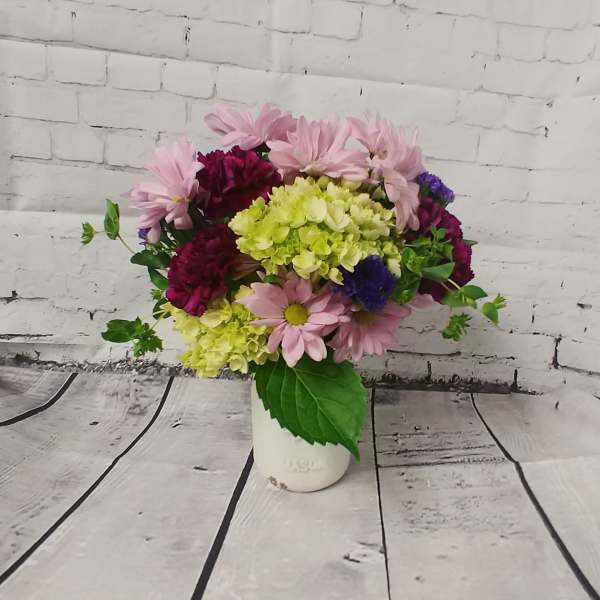 Pink daisies and hydrangeas in a white vase