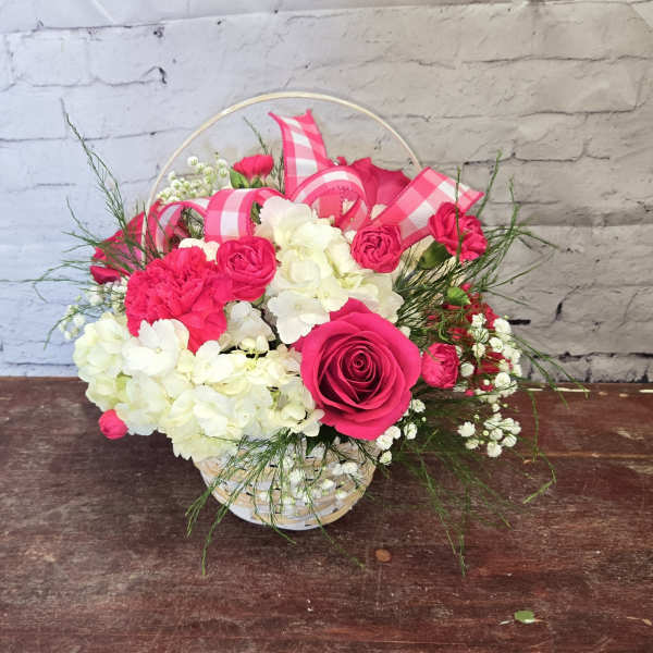 Pink roses and white hydrangeas in a basket with pink ribbon