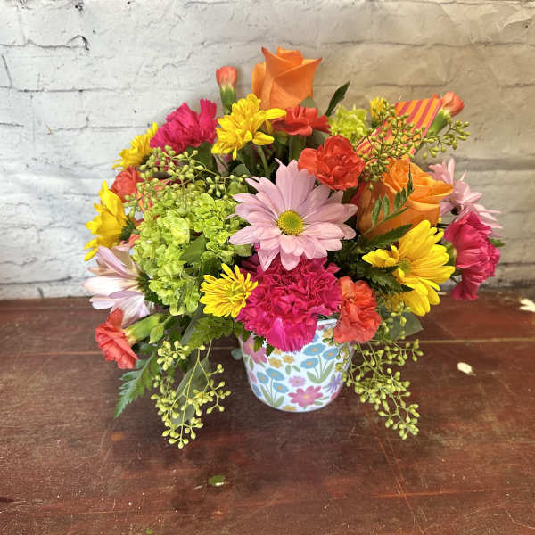 Colorful mixed flower bouquet in a floral-patterned mug