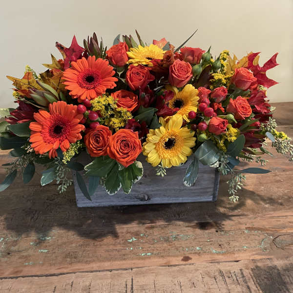 Rectangular floral arrangement with orange, yellow, and red blooms in a wooden box