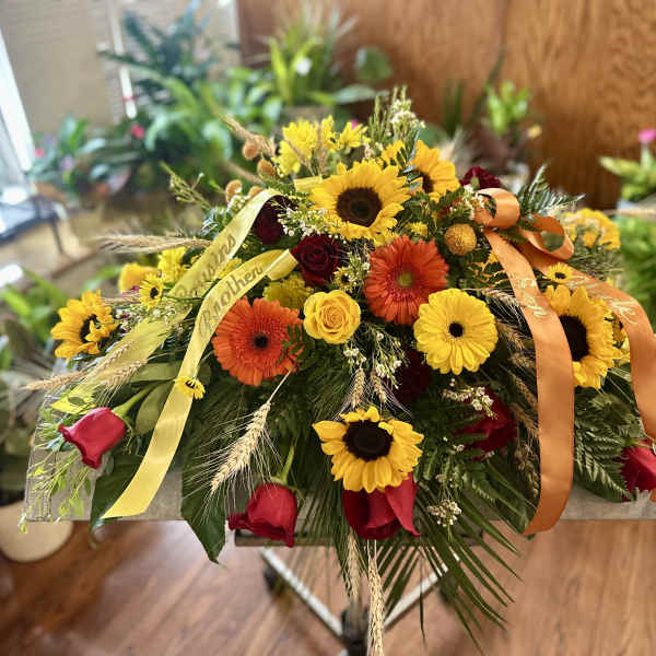 Mixed bouquet with sunflowers, gerbera daisies, and roses on a stand