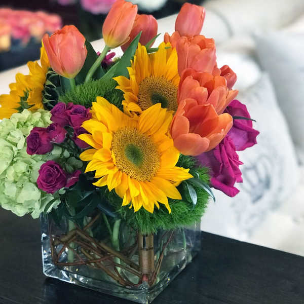 Colorful bouquet with sunflowers, tulips, roses, and hydrangea in a glass vase