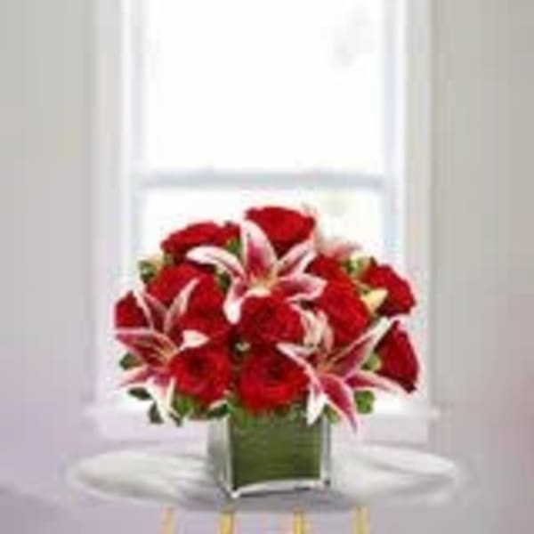 Red roses and pink lilies in a square glass vase