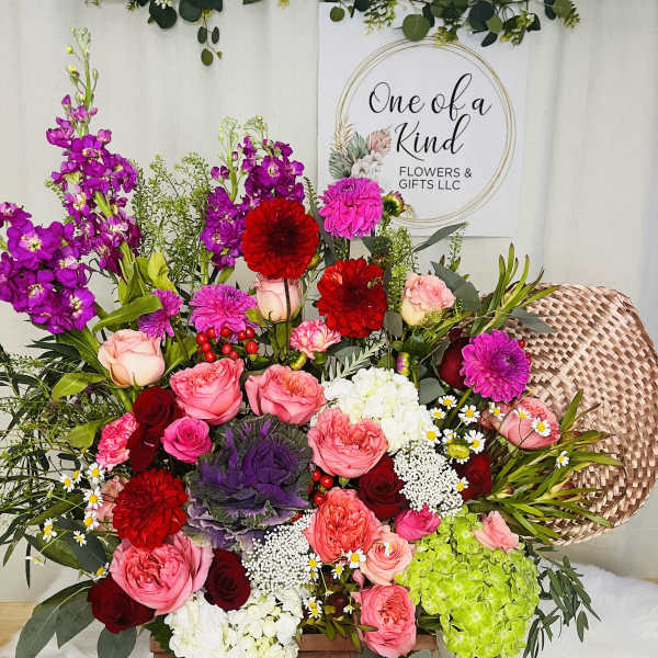 Mixed bouquet in a wooden basket with pink, red, purple, and white flowers