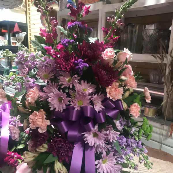 Large purple and pink floral arrangement with a satin ribbon