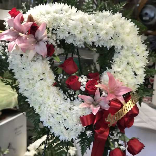 Heart-shaped floral wreath with white chrysanthemums, red roses, and pink lilies