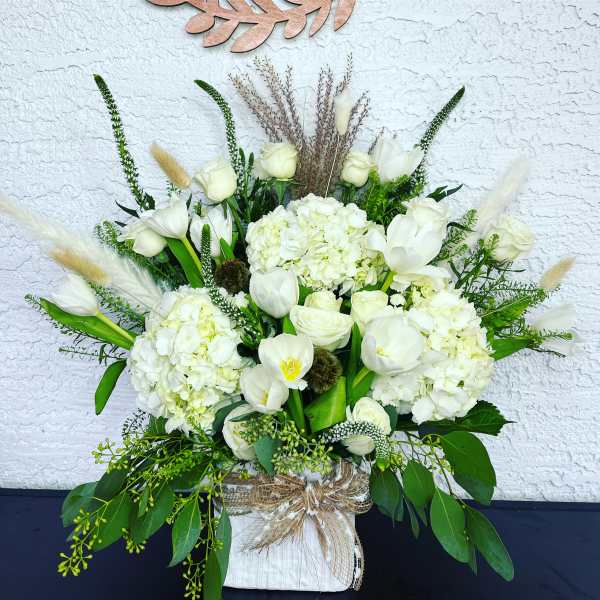 White floral arrangement with tulips and hydrangeas in a wrapped container
