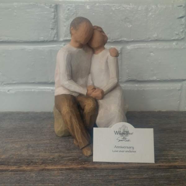 Wooden figurine of a seated couple embracing, with an anniversary card