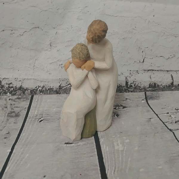 Two carved figurines of a woman and child in white robes