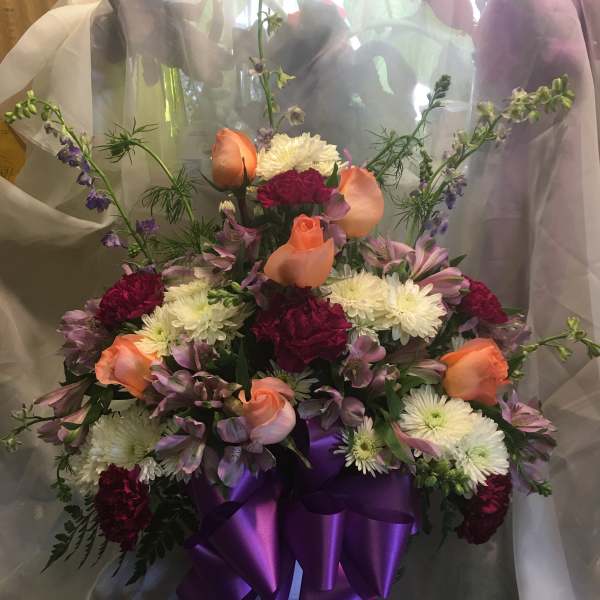 Bouquet of peach roses, white mums, and purple flowers in a white vase