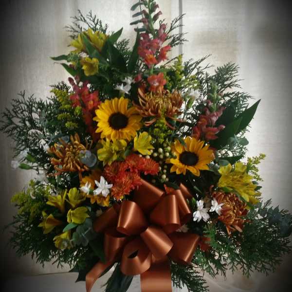 Mixed bouquet with sunflowers and orange blooms tied with a copper ribbon
