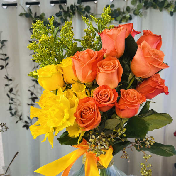 Bouquet of orange and yellow roses in a glass vase with ribbon