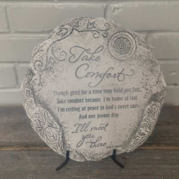 Round memorial plaque on a stand with the words "Take Comfort"