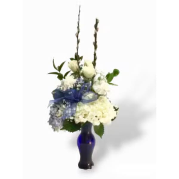 White floral arrangement in a blue glass vase with tall stems