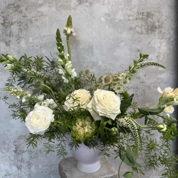 White roses and mixed white flowers in a white vase