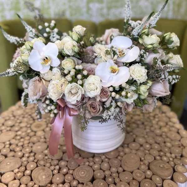 Pastel bouquet of roses and white orchids in a white vase