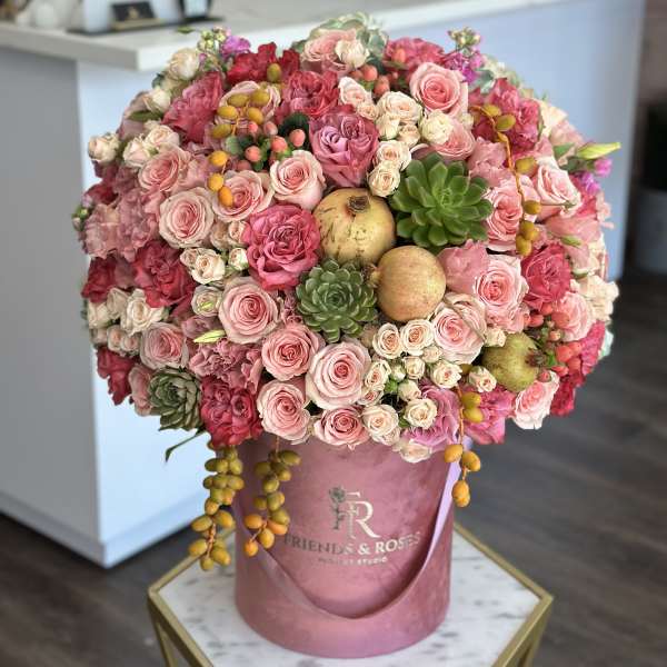 Pink rose bouquet in a round hatbox with succulents and fruit accents