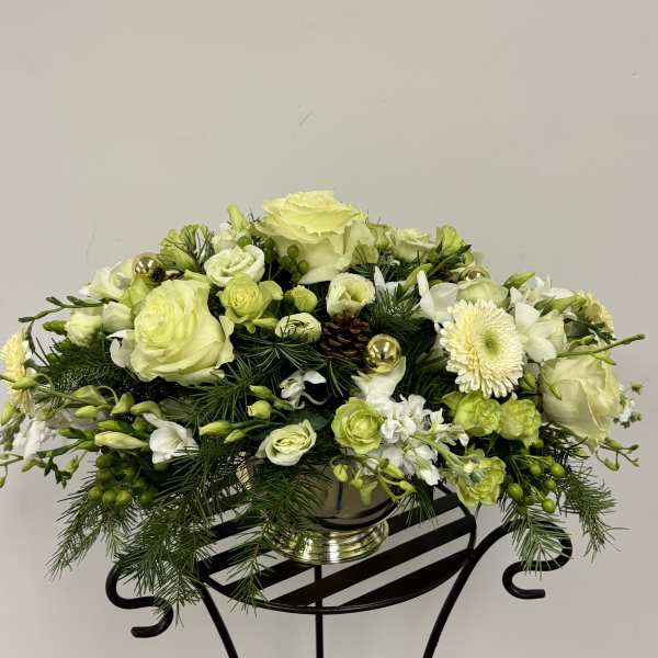 Low floral centerpiece with pale green and white blooms in a silver vase