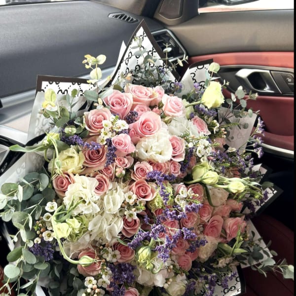 Large bouquet of pink and white roses with purple filler flowers