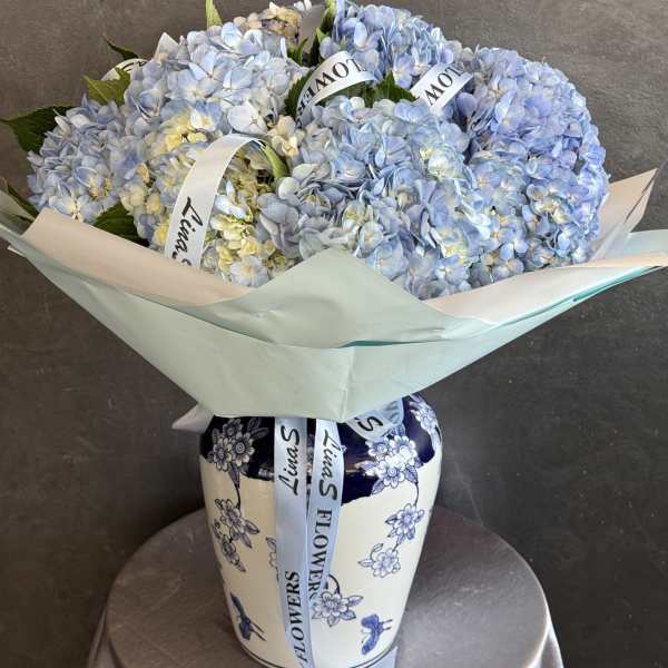Bouquet of pale blue hydrangeas in a decorative vase