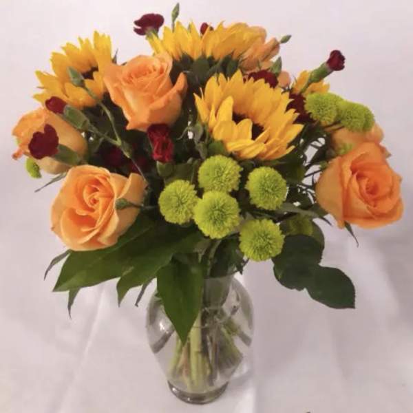 Bouquet of orange roses and yellow sunflowers in a glass vase