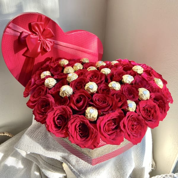 Heart-shaped box of red roses with gold-wrapped chocolates