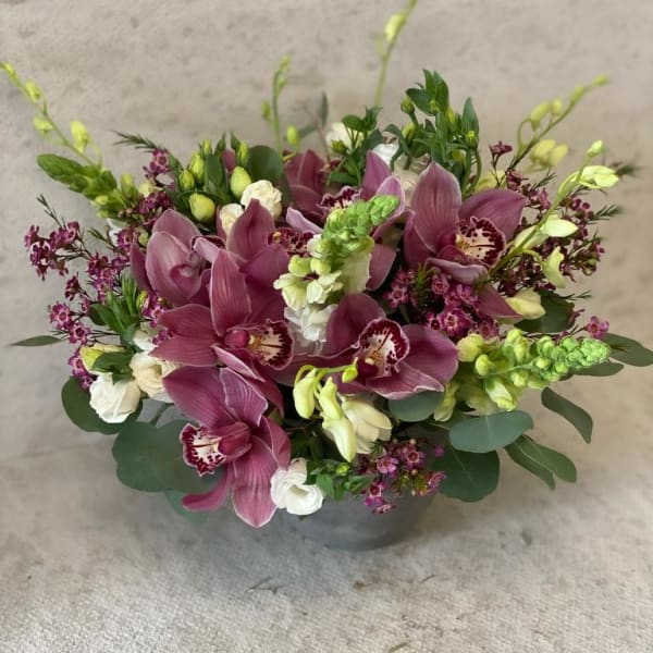 Purple orchids and white blooms arranged in a low vase