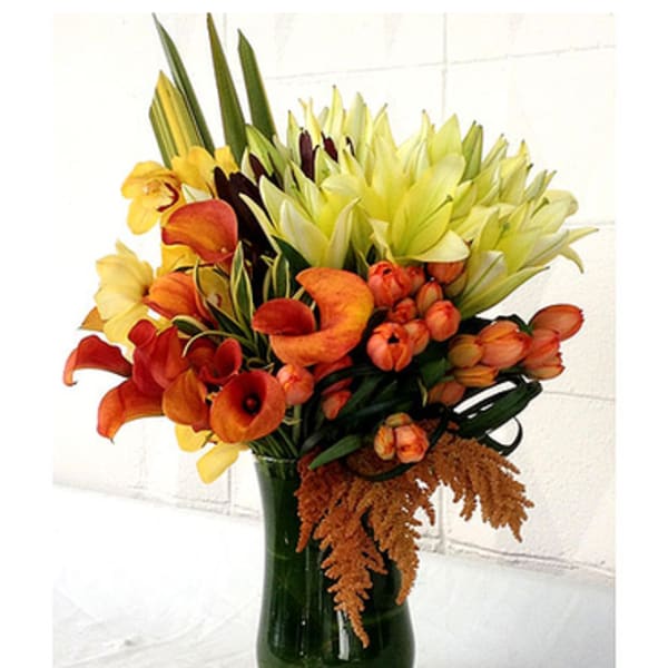 Orange and yellow calla lilies arranged in a dark glass vase
