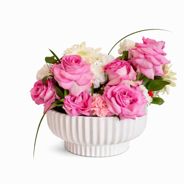 Pink roses and white flowers arranged in a white ceramic bowl