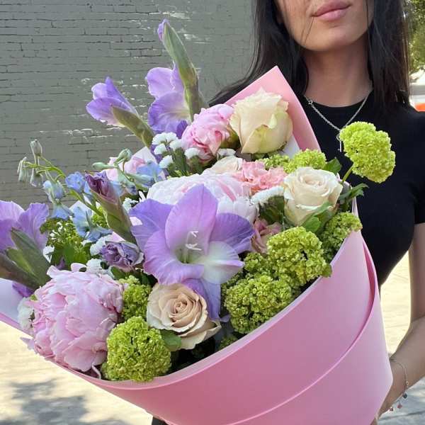 Large pastel bouquet with pink, purple, and cream flowers wrapped in pink paper