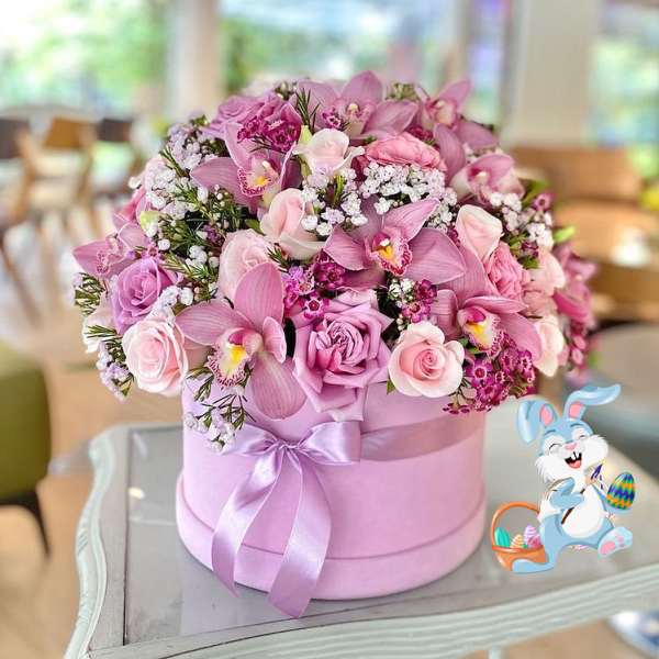 Pink floral arrangement in a lavender hatbox with a ribbon and Easter bunny decoration