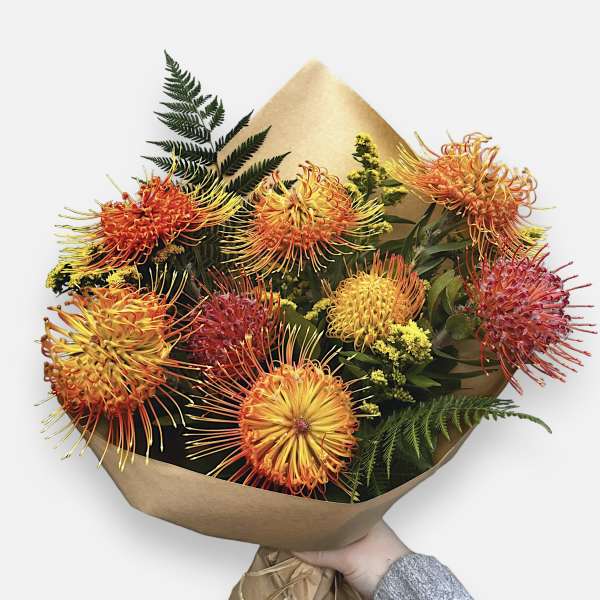Bouquet of orange and yellow spider chrysanthemums wrapped in brown paper