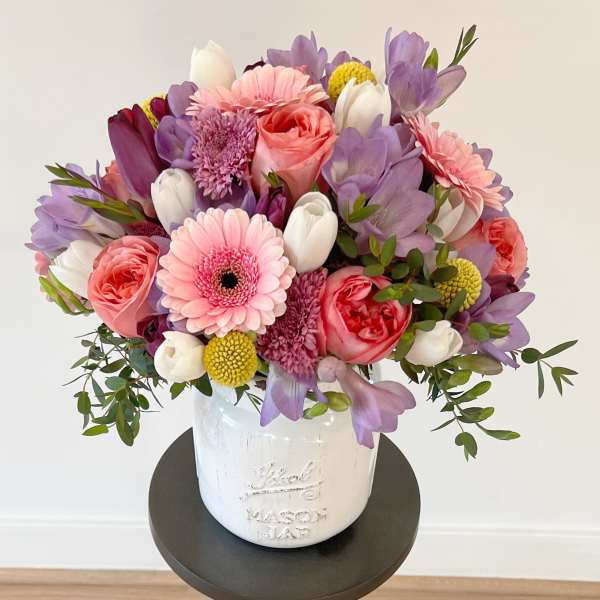 Pink, purple, and white bouquet in a white ceramic vase